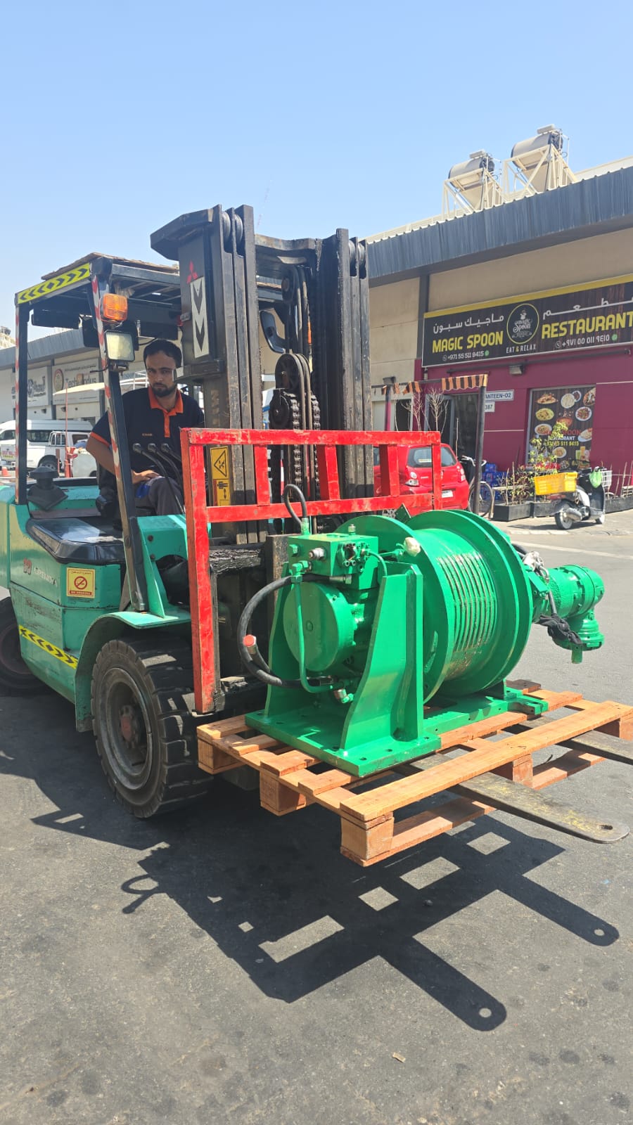 Green davit crane winch assembly being handled by forklift